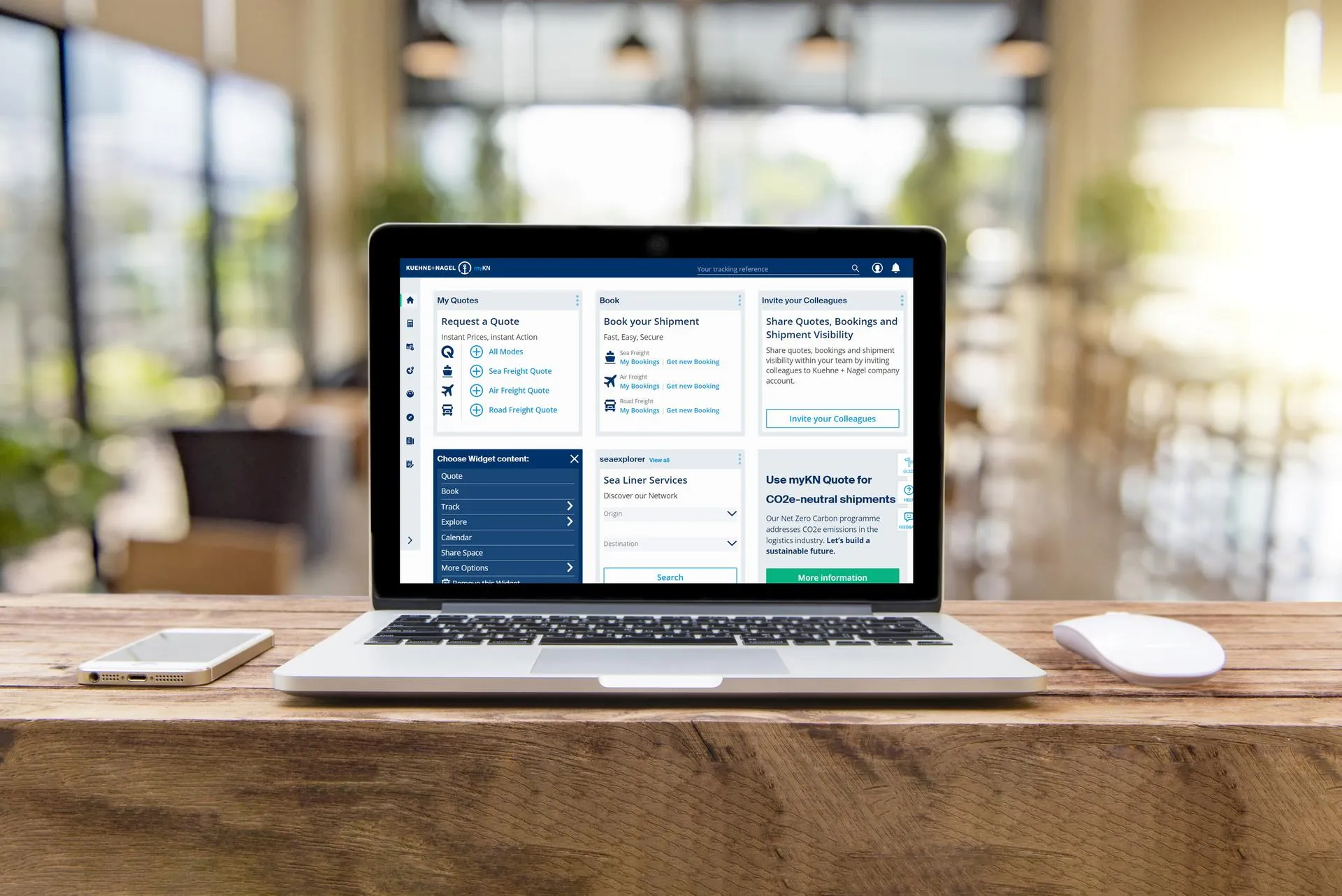 A laptop displaying the MyKN platform is positioned next to a mobile phone and wireless mouse.