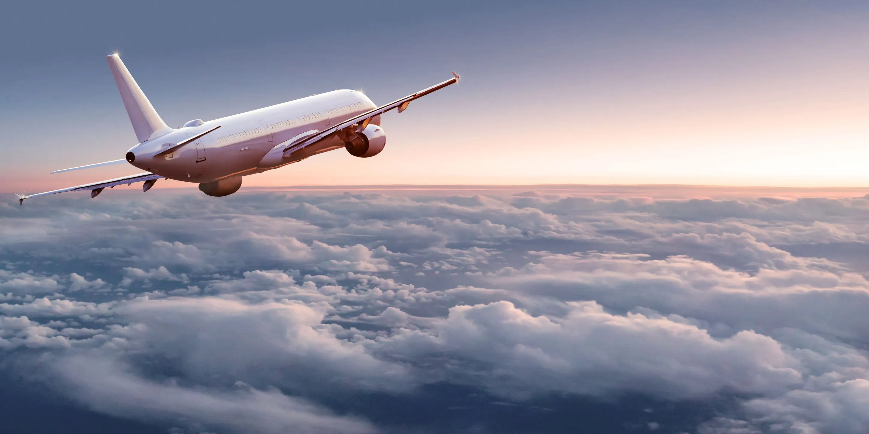 Airplane flying above the clouds during sunset.